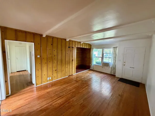 a view of an empty room with wooden floor and a window