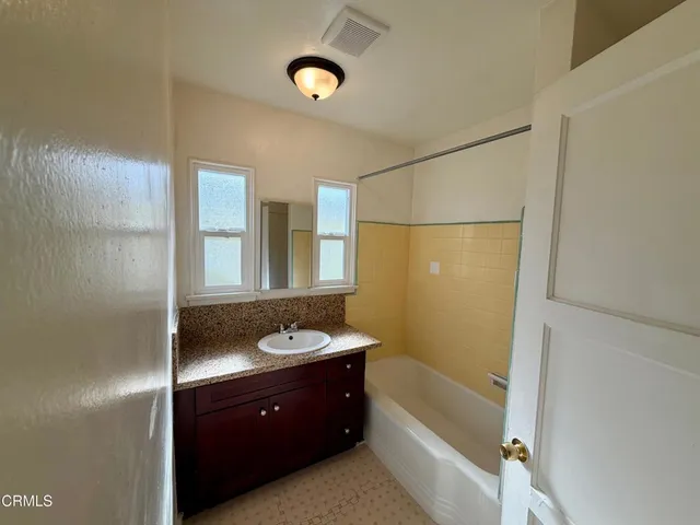 a bathroom with a granite countertop sink a mirror and a bathtub