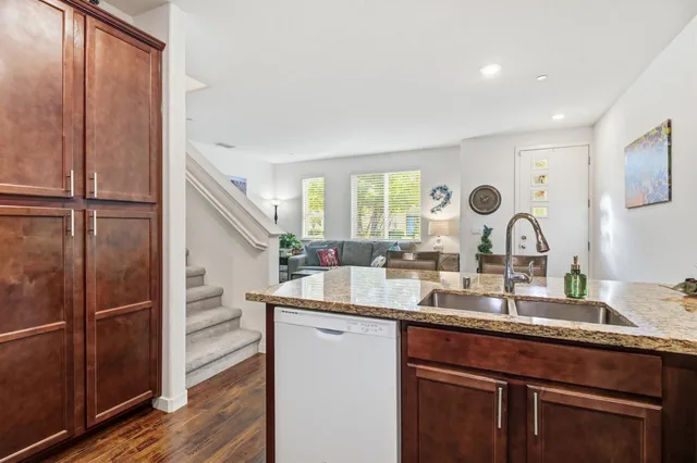 a kitchen with kitchen island granite countertop a sink cabinets and wooden floor