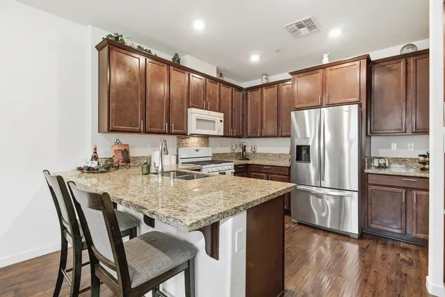 a kitchen with granite countertop a refrigerator and wooden cabinets