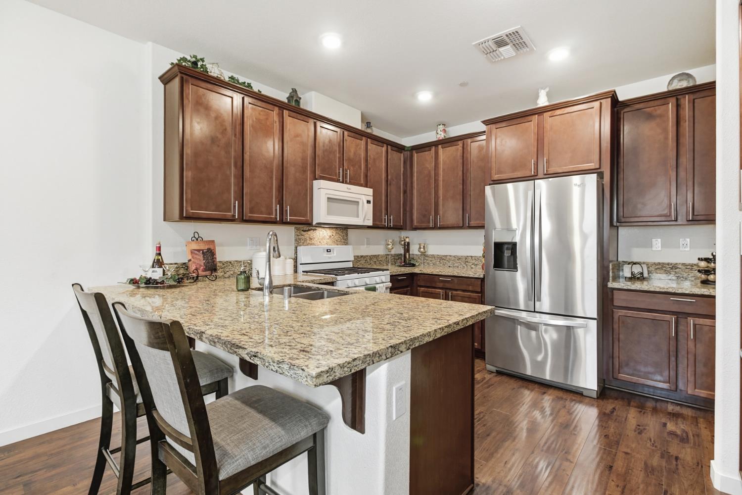 3215 Bridgeway Drive Rancho Cordova, CA 95670 - Photo 3 of 32 a kitchen with granite countertop a refrigerator and wooden cabinets