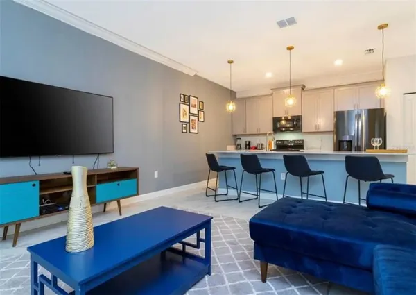 a living room with furniture a flat screen tv and kitchen view