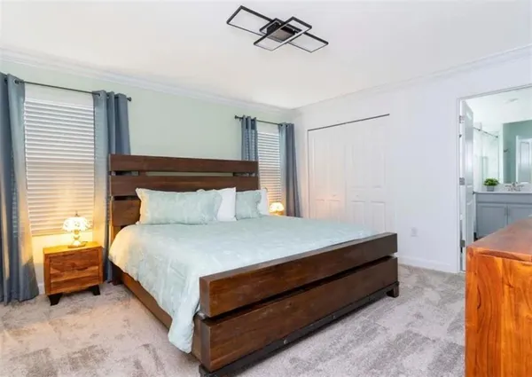a bed sitting in a bedroom next to a window and a chandelier
