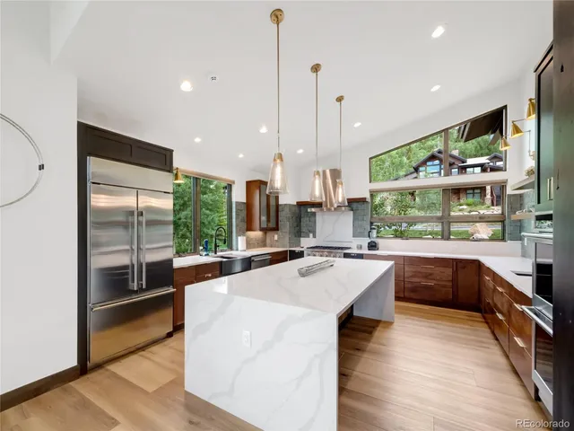 a large kitchen with kitchen island a large window a counter space and stainless steel appliances
