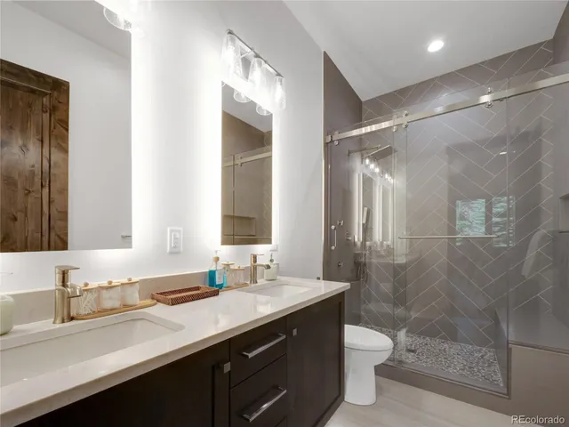 a bathroom with a double vanity sink toilet and shower