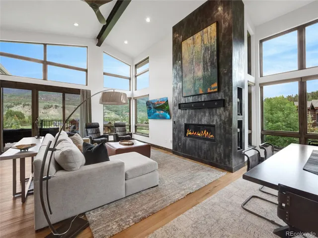 a living room with furniture fireplace and large windows