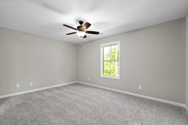 an empty room with a window and a ceiling fan