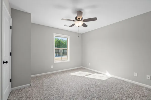 an empty room with windows and fan
