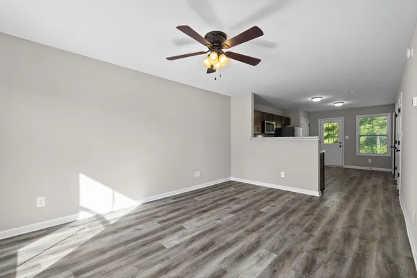 a view of an empty room with window and wooden floor