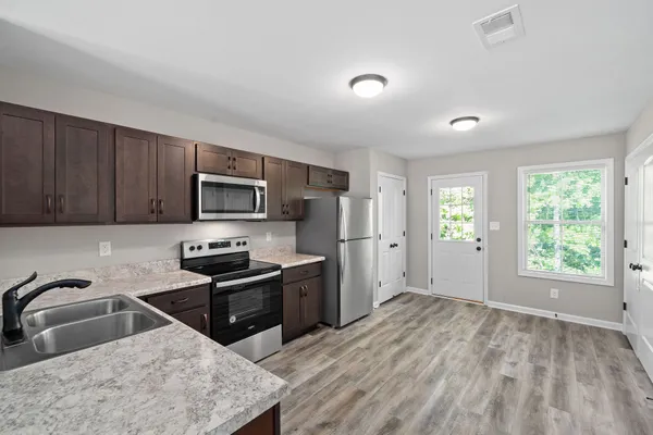 a kitchen with stainless steel appliances granite countertop a sink stove refrigerator and window