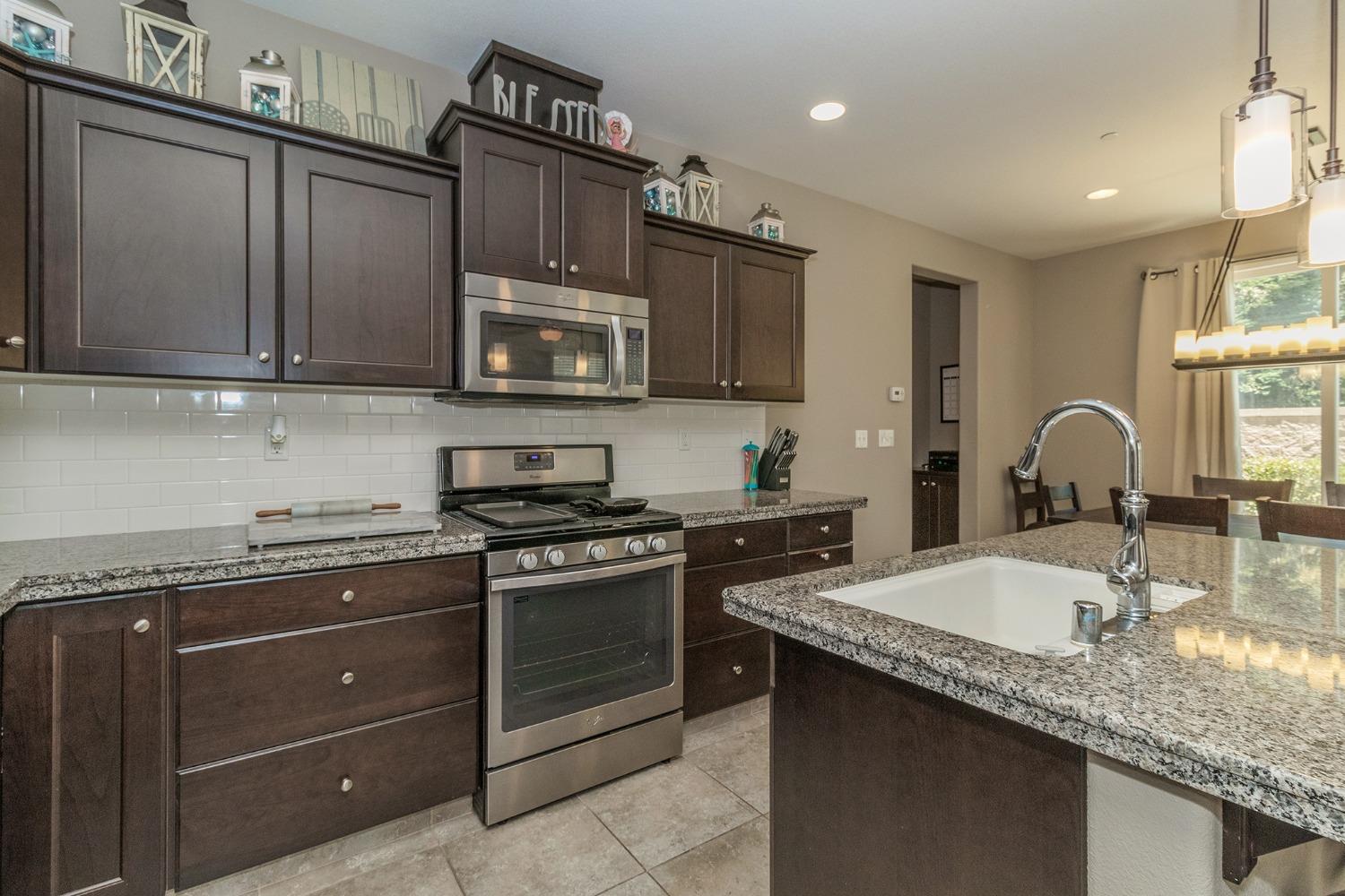 3263 Monviso Lane Clovis, CA 93619 - Photo 9 of 30 a kitchen with granite countertop stainless steel appliances a stove sink and cabinets