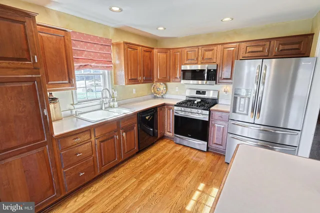 a kitchen with stainless steel appliances granite countertop a refrigerator a sink dishwasher a stove top oven a refrigerator and cabinets