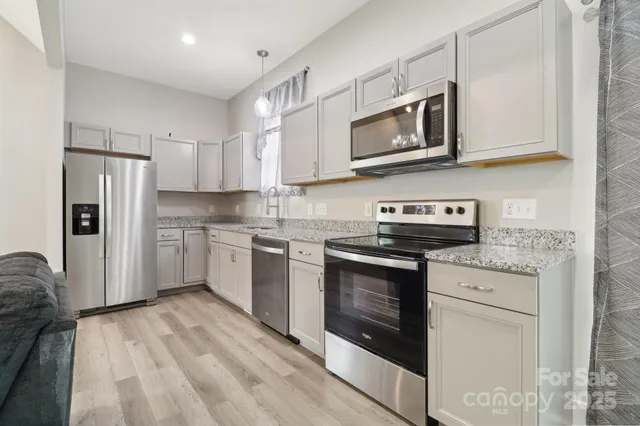 a kitchen with stainless steel appliances granite countertop a stove a sink and a microwave