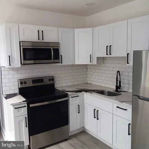 a kitchen with stainless steel appliances a stove a refrigerator a sink and white cabinets