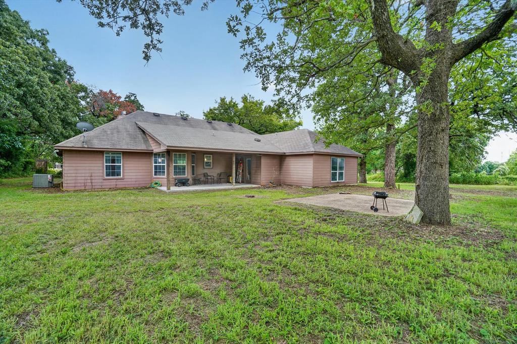 1654 Ranger Highway Weatherford, TX 76088 - Photo 26 of 31 Expansive rear yard featuring mature trees, a covered patio, and a concrete pad