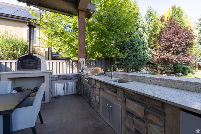 687 South 2080th Street East Springville, UT 84663 - Photo 117 of 149 Outdoor kitchen featuring a built-in pizza oven, integrated grill, stainless steel cabinetry, and a sink with a gooseneck faucet