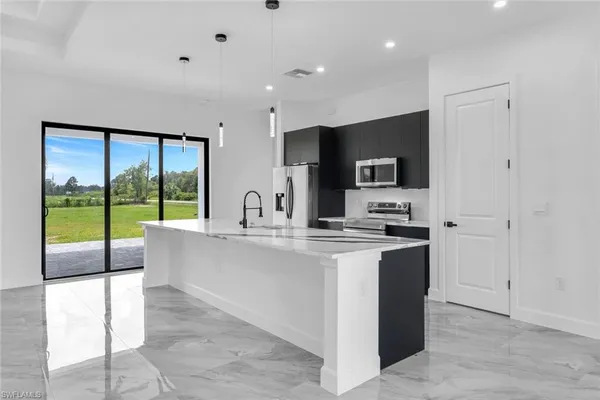 a living room with stainless steel appliances a large window and a flat screen tv