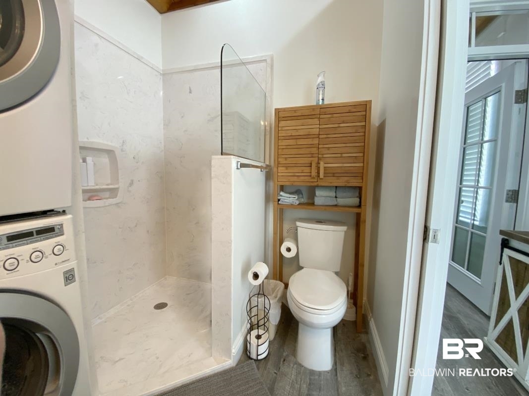 28888 Canal Road, Unit 77 Orange Beach, AL 36561 - Photo 7 of 23 Bathroom featuring a walk-in shower with a glass partition and white marble-look surround, wood-finish flooring, and a white toilet