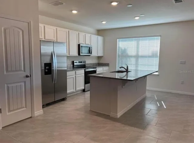 a kitchen with stainless steel appliances granite countertop a refrigerator and a stove top oven