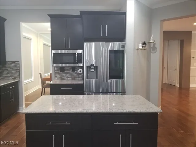 a kitchen with kitchen island a sink refrigerator and wooden floor