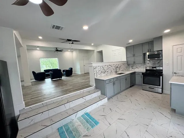 a large kitchen with granite countertop a stove refrigerator and a sink