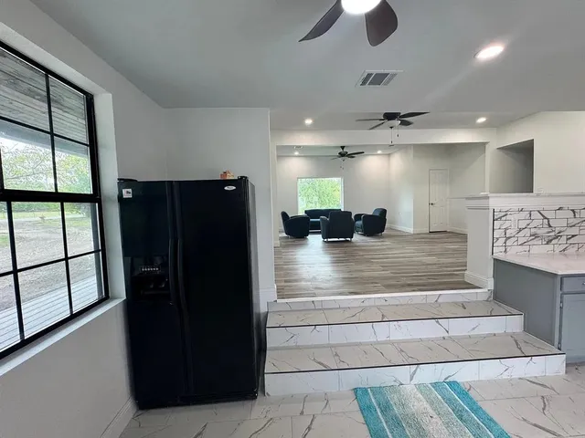 a living room with stainless steel appliances furniture a window and wooden floor