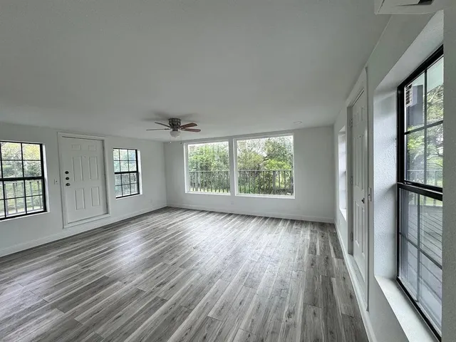 a view of an empty room with kitchen and window