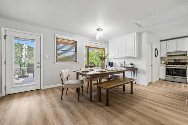 a kitchen with a table chairs a sink dishwasher window and cabinets with wooden floor