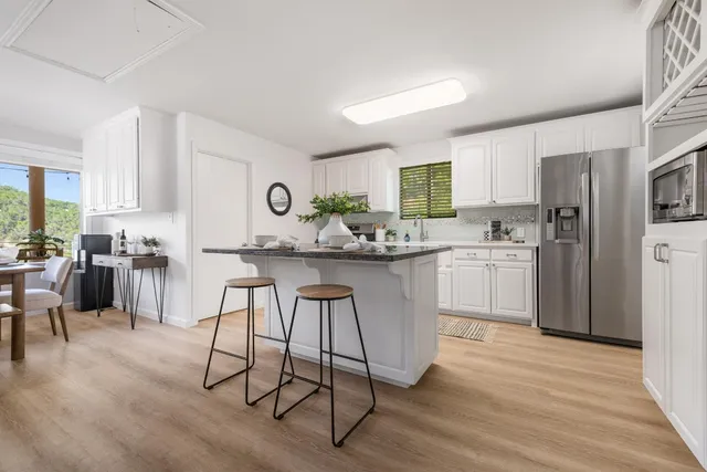 a kitchen with stainless steel appliances kitchen island hardwood floor sink and cabinets