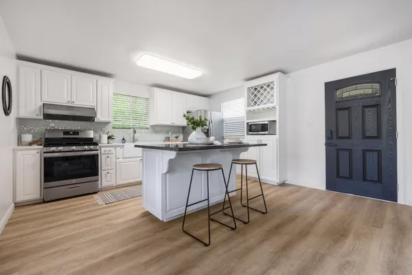 a kitchen with stainless steel appliances a stove a sink cabinets and a wooden floor