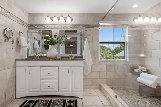 a bathroom with a granite countertop sink a mirror and a shower