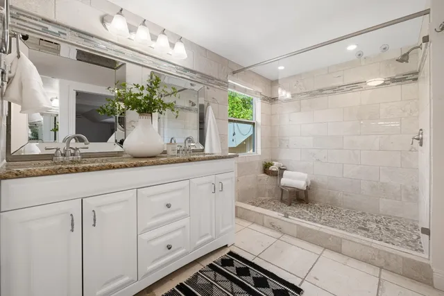 a bathroom with a granite countertop sink a mirror and shower