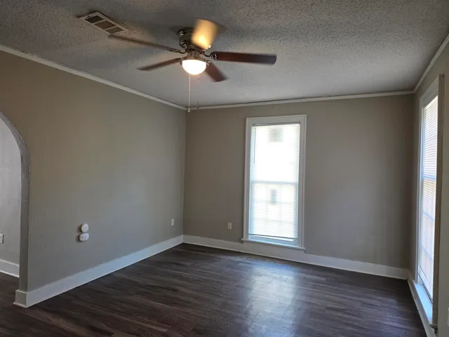 an empty room with wooden floor fan and windows