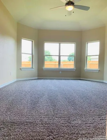an empty room with a window and a ceiling fan