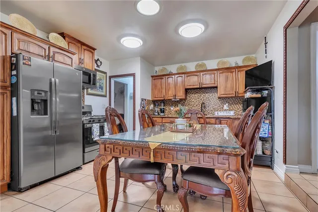 a kitchen with stainless steel appliances granite countertop a refrigerator a stove a sink a dining table and chairs