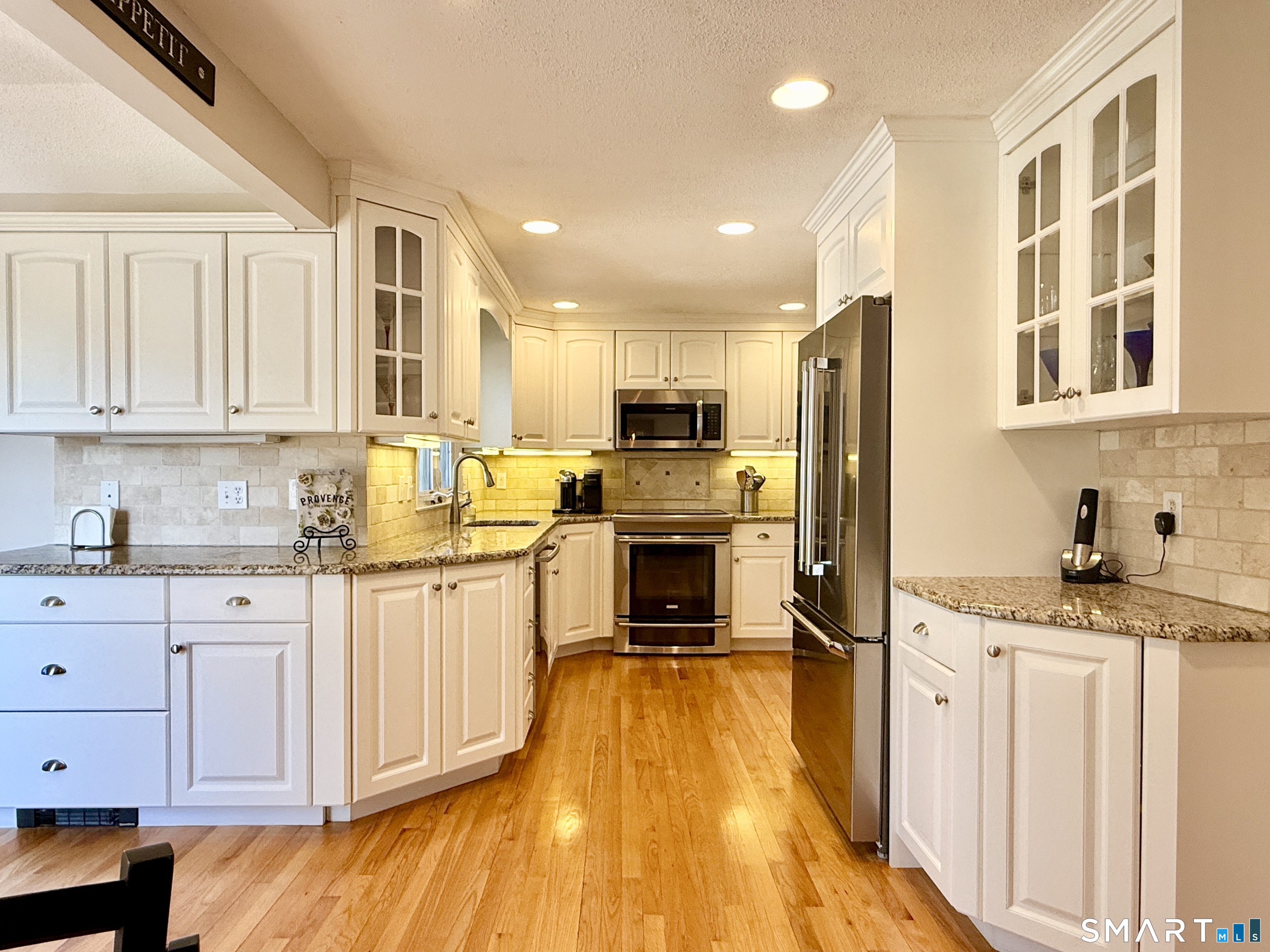 17 Sunnybrook Drive Avon, CT 06001 - Photo 11 of 40 a kitchen with granite countertop a refrigerator a stove and white cabinets with wooden floor