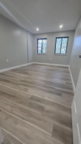 a view of an empty room with window and hardwood floor