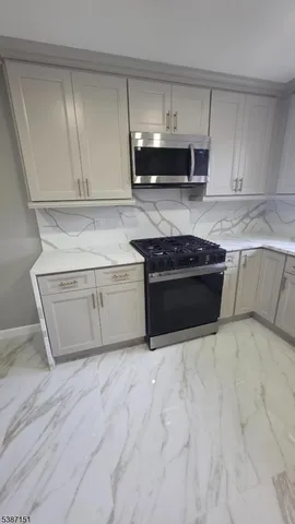 a kitchen with granite countertop a stove and a microwave