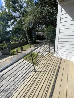a view of a balcony with wooden floor and large trees