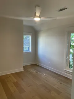 an empty room with wooden floor and windows