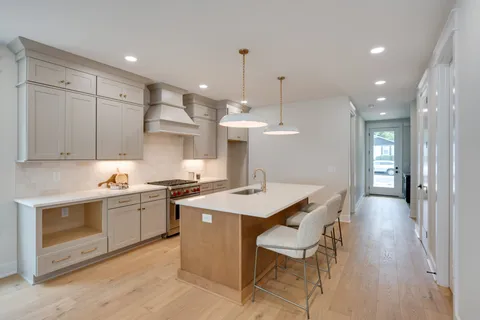 a kitchen with stainless steel appliances kitchen island granite countertop a stove a sink a refrigerator and a dining table with wooden floor