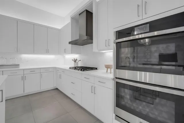 a large kitchen with stainless steel appliances a sink and a refrigerator