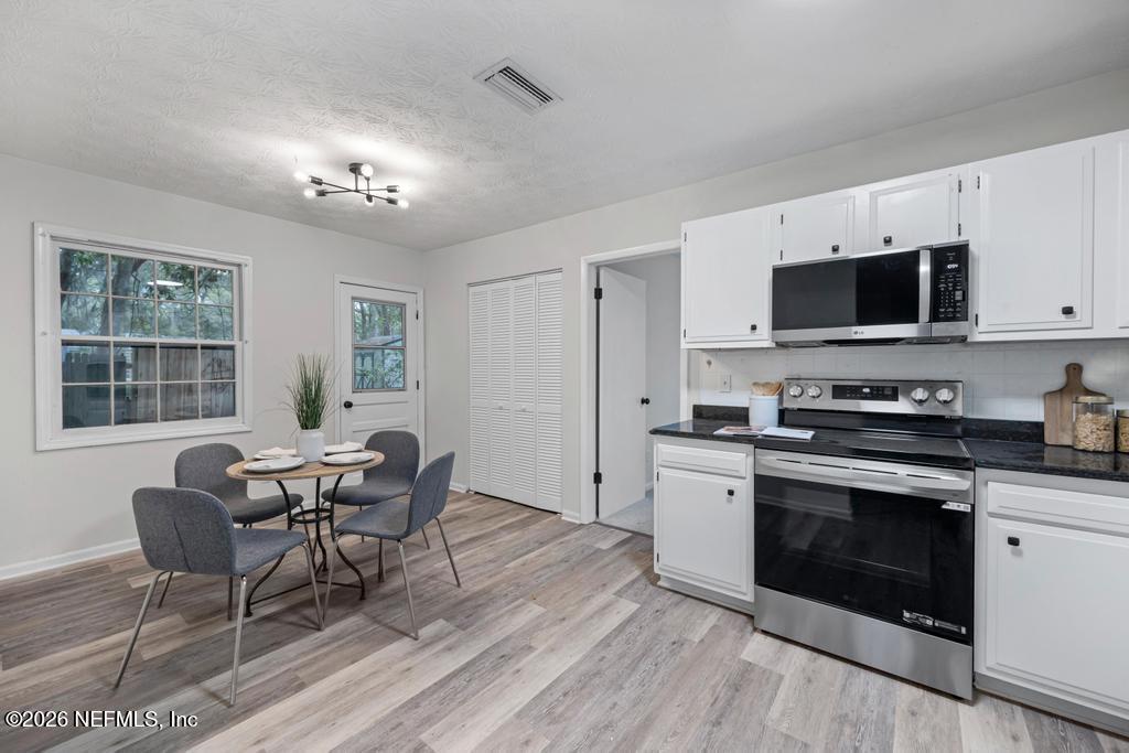 4634 Whimbrel Lane Fernandina Beach, FL 32034 - Photo 14 of 42 a kitchen with stainless steel appliances a stove a sink dishwasher a dining table and chairs