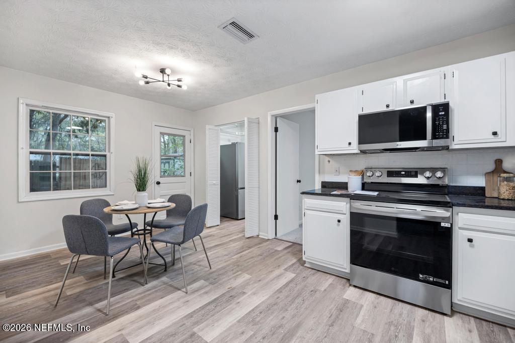 4634 Whimbrel Lane Fernandina Beach, FL 32034 - Photo 5 of 42 a kitchen with stainless steel appliances granite countertop a stove top oven a sink dishwasher a dining table and chairs with wooden floor