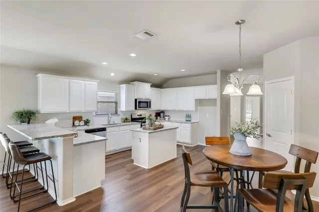 a kitchen with a dining table chairs stainless steel appliances and cabinets
