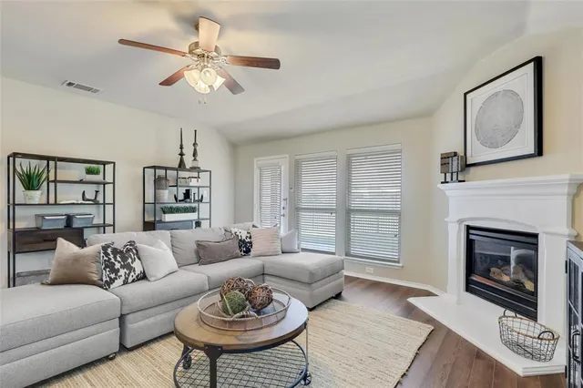 a living room with furniture a fireplace and a ceiling fan
