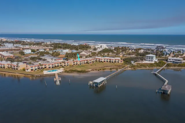 an aerial view of ocean and residential houses with outdoor space