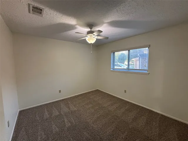 an empty room with a window and a fan