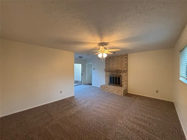 an empty room with a fireplace and chandelier fan
