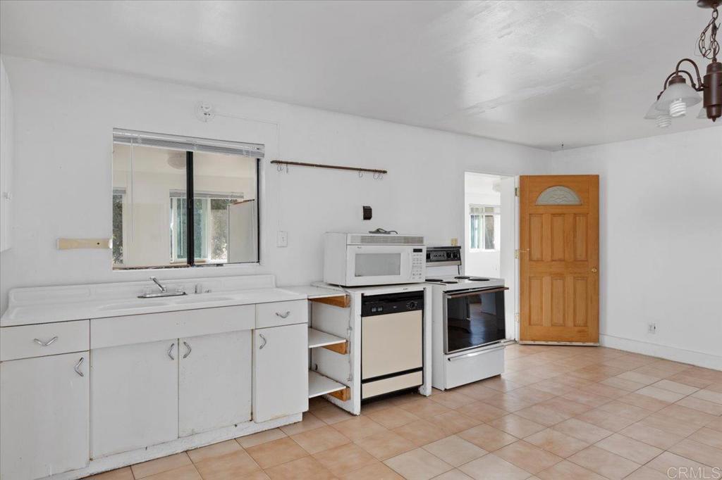 34174 Hampton Road Pauma Valley, CA 92061 - Photo 6 of 20 a kitchen with white cabinets and white appliances